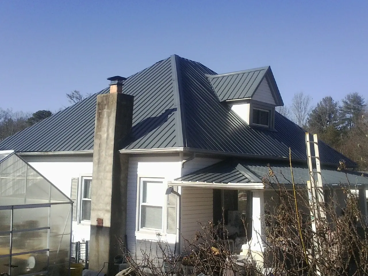 Dark blue standing seam metal roof on a white farmhouse with dormer — Slate & Tile Roof Repair by Roofing Brothers in Mabton
