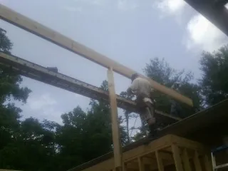 Carpenter setting a ridge beam over a new addition frame — Ice Dam Removal by Roofing Brothers in Mabton