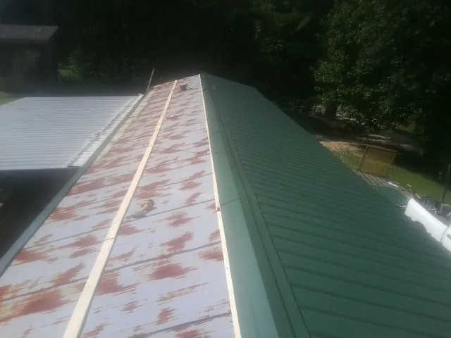 Old rusted panels beside newly installed green metal roofing — Wind Damage Roof Repair by Roofing Brothers in Mabton