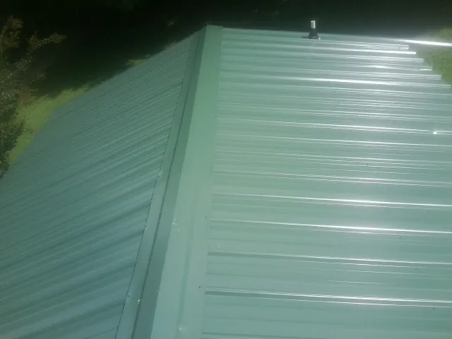 New green metal panels meeting at the ridge of a roof — Flat Roof Repair work by our crew in Mabton