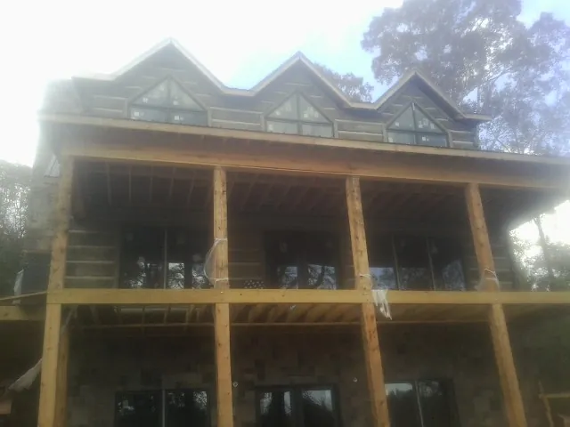 Dormers and porch framing on a large log home under construction — Roof Coating work by our crew in Mabton