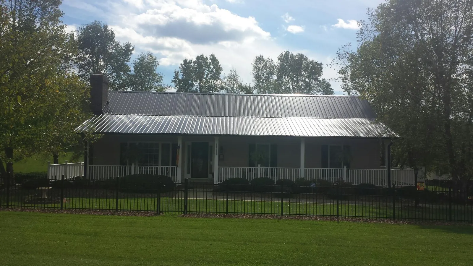 Gray metal roof on a brick ranch with a full width front porch — Gutter Guard Installation work by our crew in Mabton