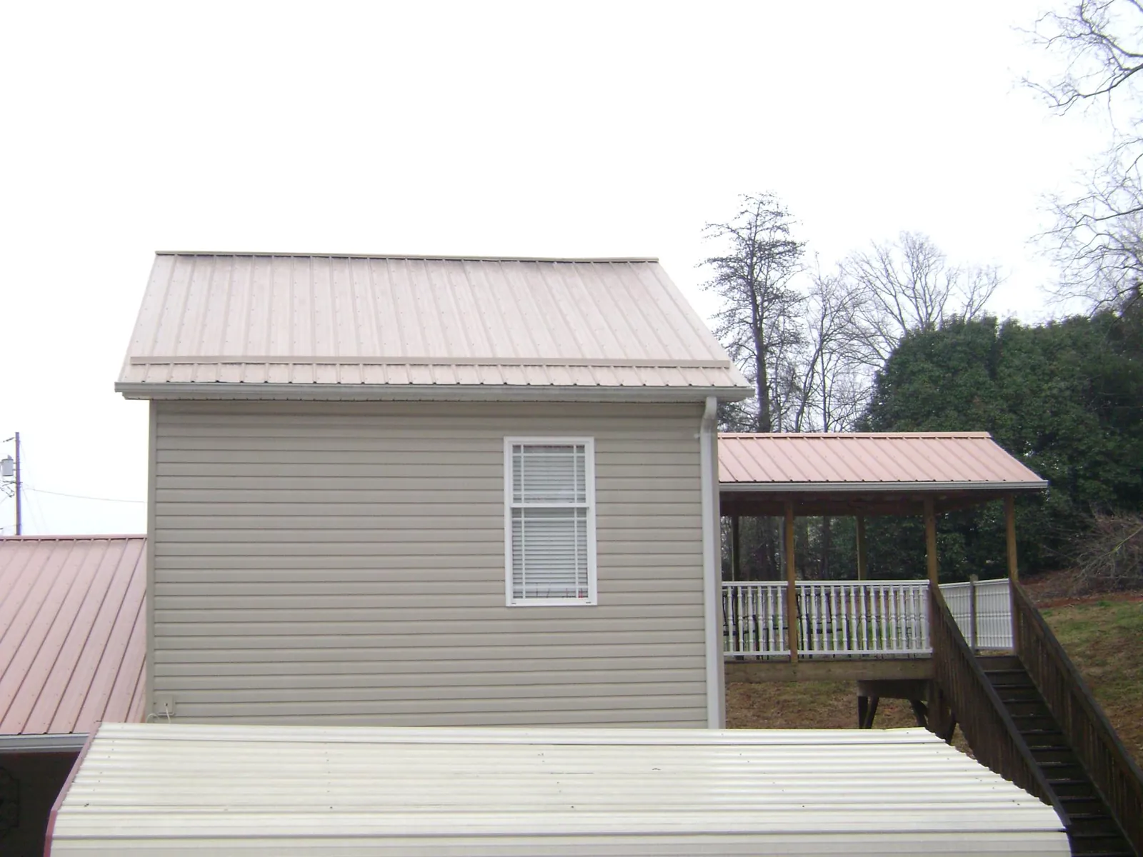 Tan metal roofs on a two story addition and attached porch, from a Roof Replacement job in Mabton