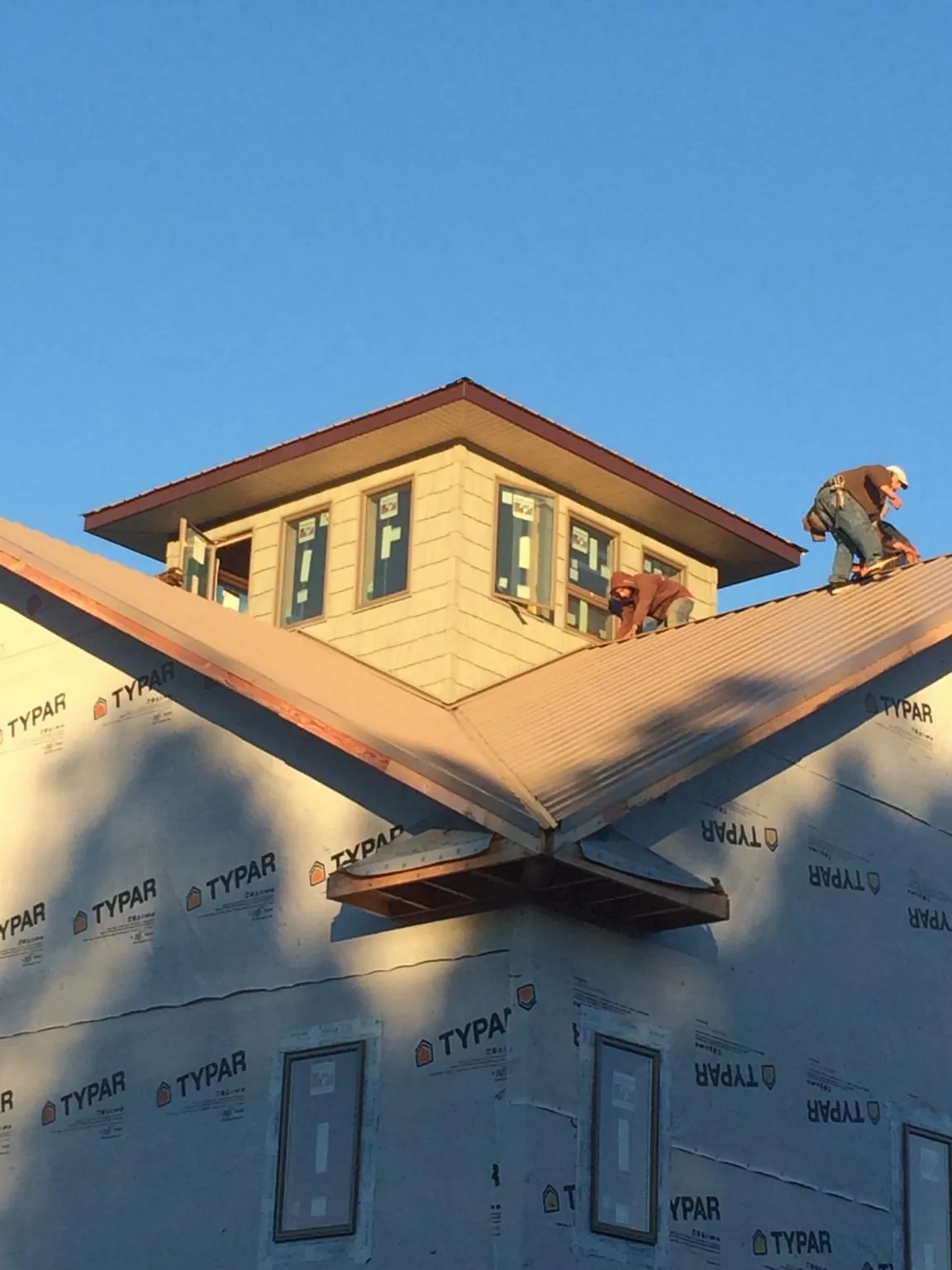 Roofers working around a rooftop cupola on a new metal roof at sunset — Roof Waterproofing in Mabton by Roofing Brothers